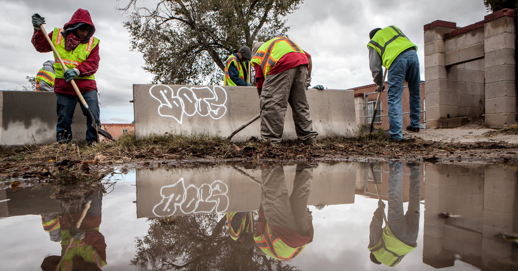 Panhandlers dug up weeds along a side street in Albuquerque as part of a new program in the city. Credit Mark Holm for The New York Times