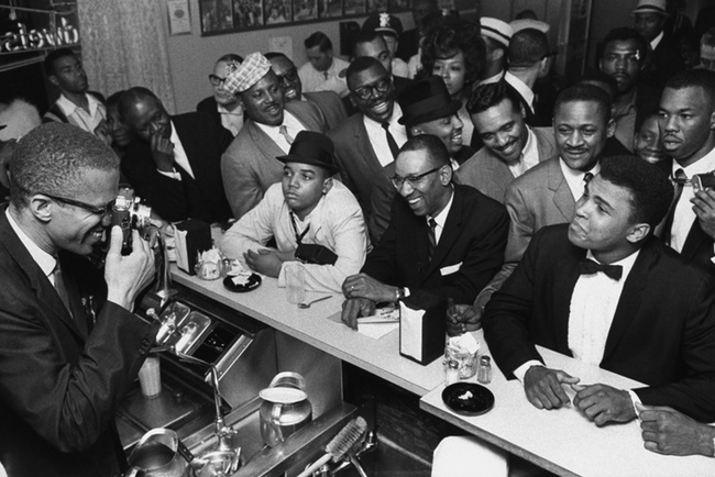 Malcolm X joking around with Ali at a diner in 1964